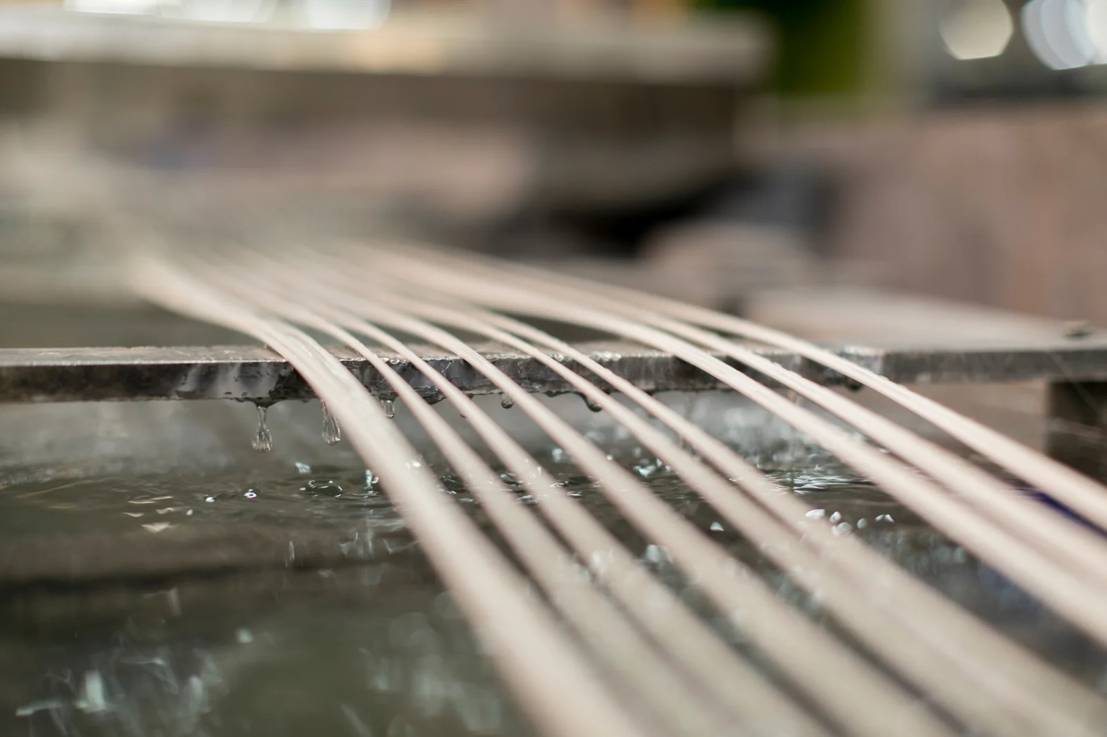 Extruded plastic strands passing through a cooling-water trough